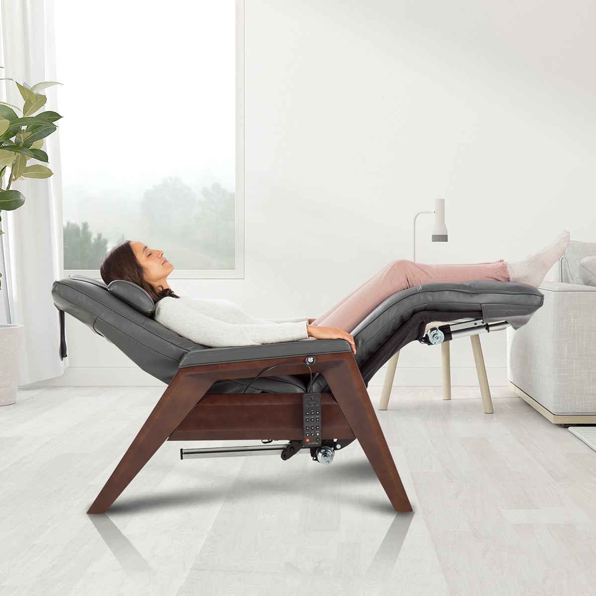 Gravis ZG Chair in zero gravity position with person relaxing in modern living room setting near window and plant