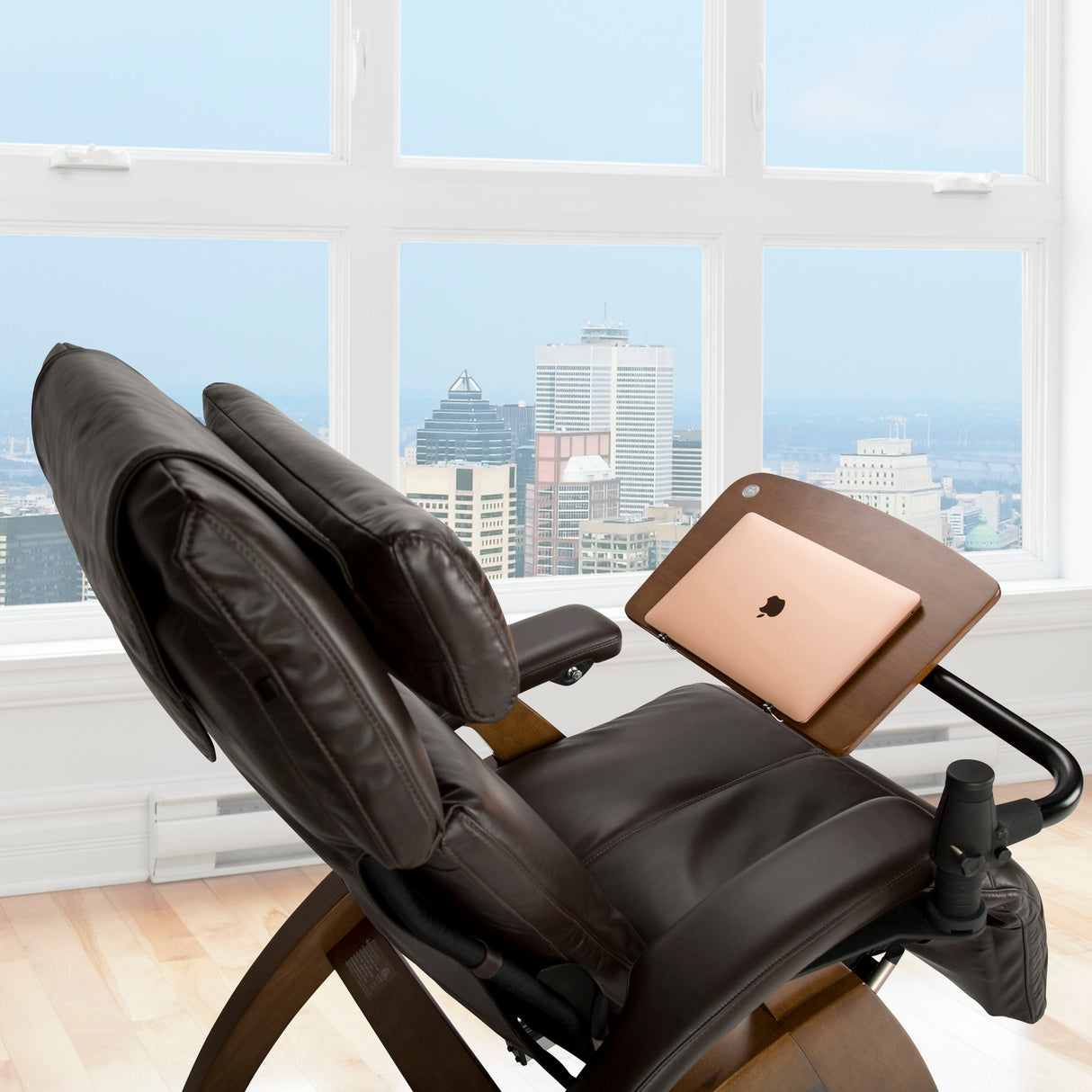 Perfect Chair Laptop Desk attached to leather recliner with laptop display, city skyline view through window behind