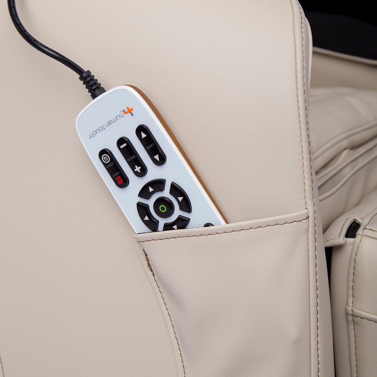 Quies Massage Chair remote control tucked in beige leather chair pocket for easy access and massage adjustments.