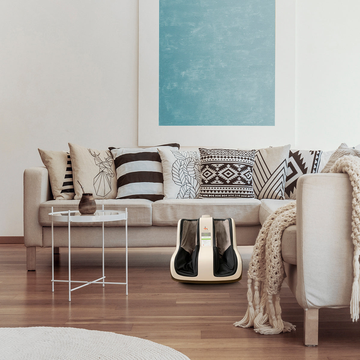 Reflex SOL Foot and Calf Massager shown in modern living room with beige couch and geometric pillows