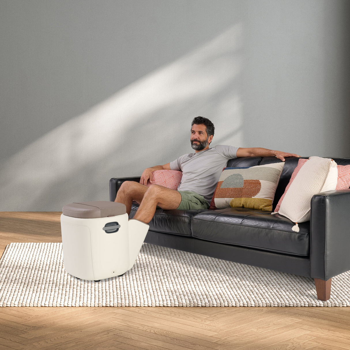 Reveal Ottoman Massager shown as stylish foot massager next to couch, demonstrating comfort and modern living room design