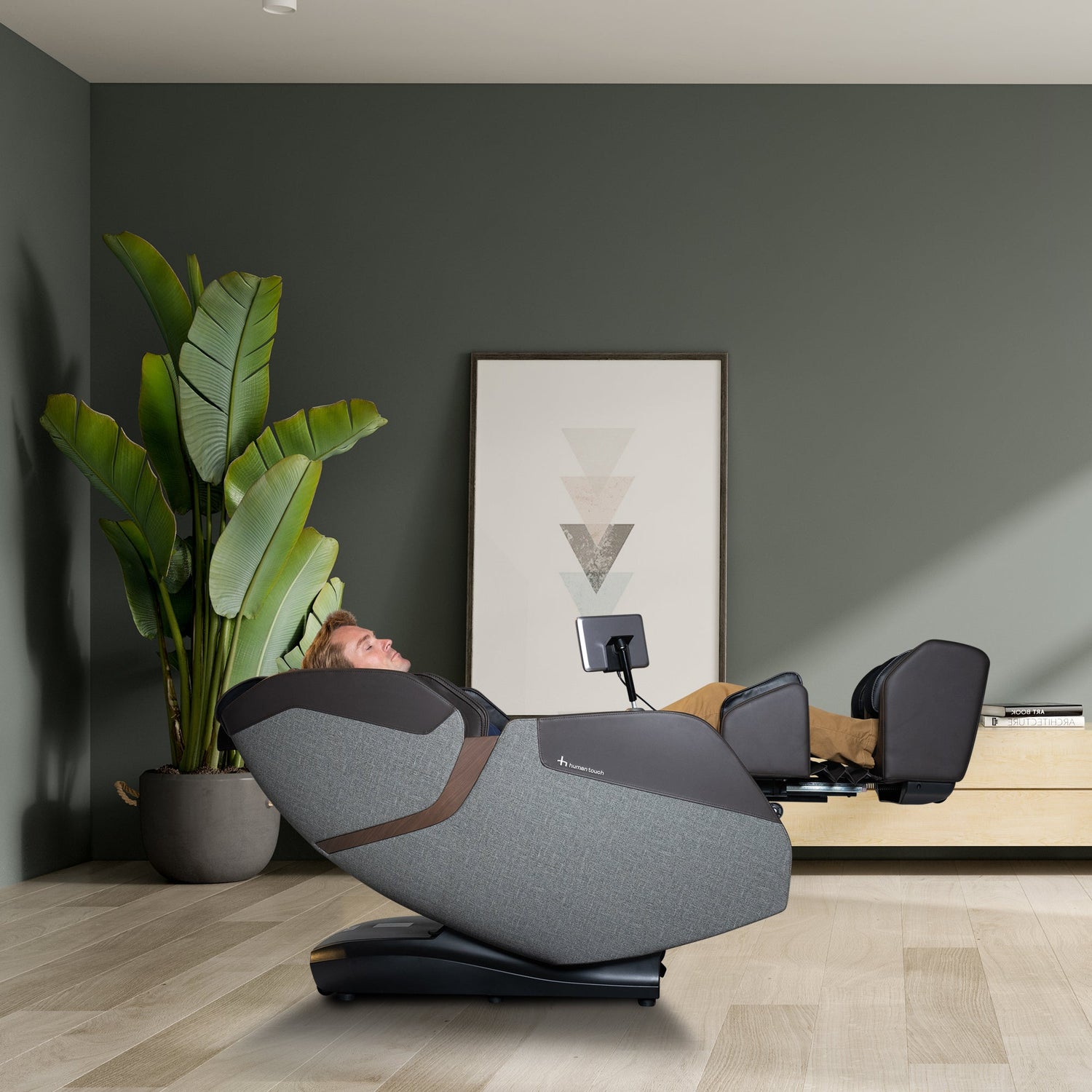 WholeBody® ROVE Massage Chair reclined with a person relaxing in a modern room with plants and artwork.